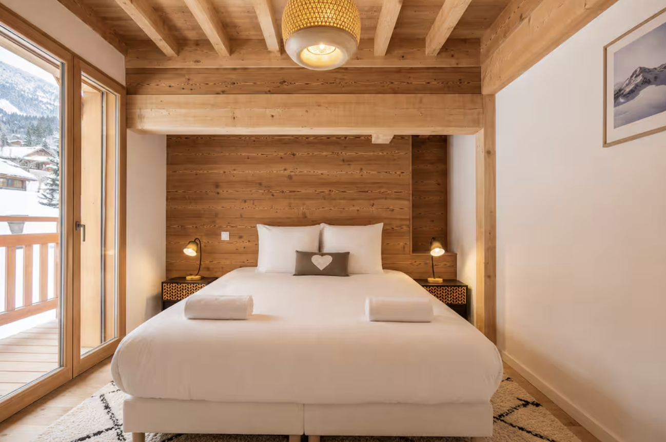 Queen bedroom with timber walls and balcony over the snow