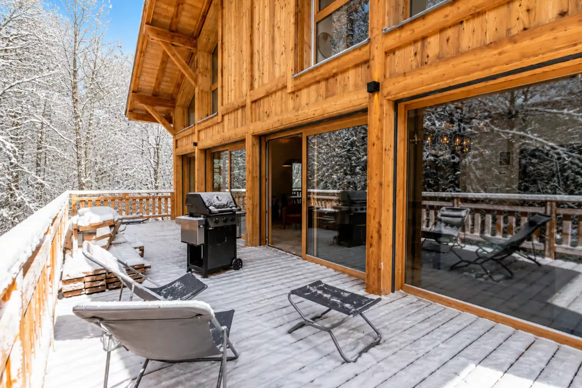 Snowy chalet terrace with loungers and forest views